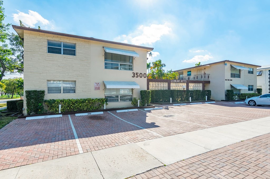 an apartment building with a parking lot and a car in front of it