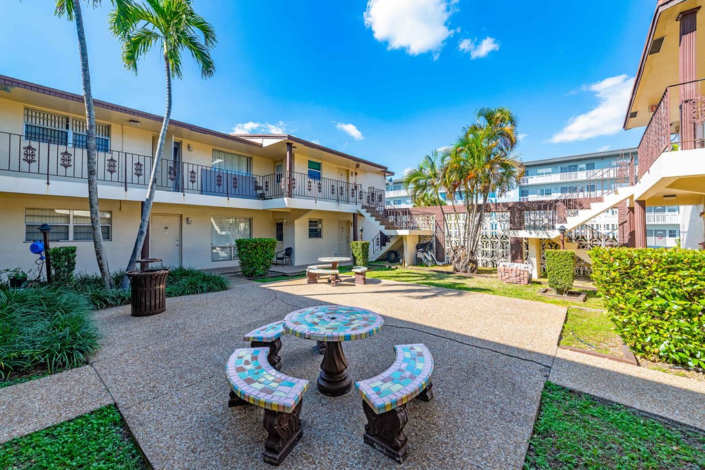 a courtyard with tables and benches in front of a building