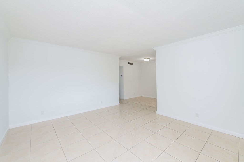 the living room and dining room of an empty house with white walls and tile floor