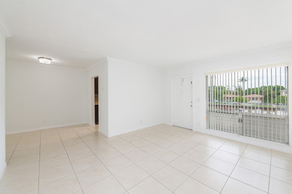 the living room of an empty apartment with a balcony and tiled floor