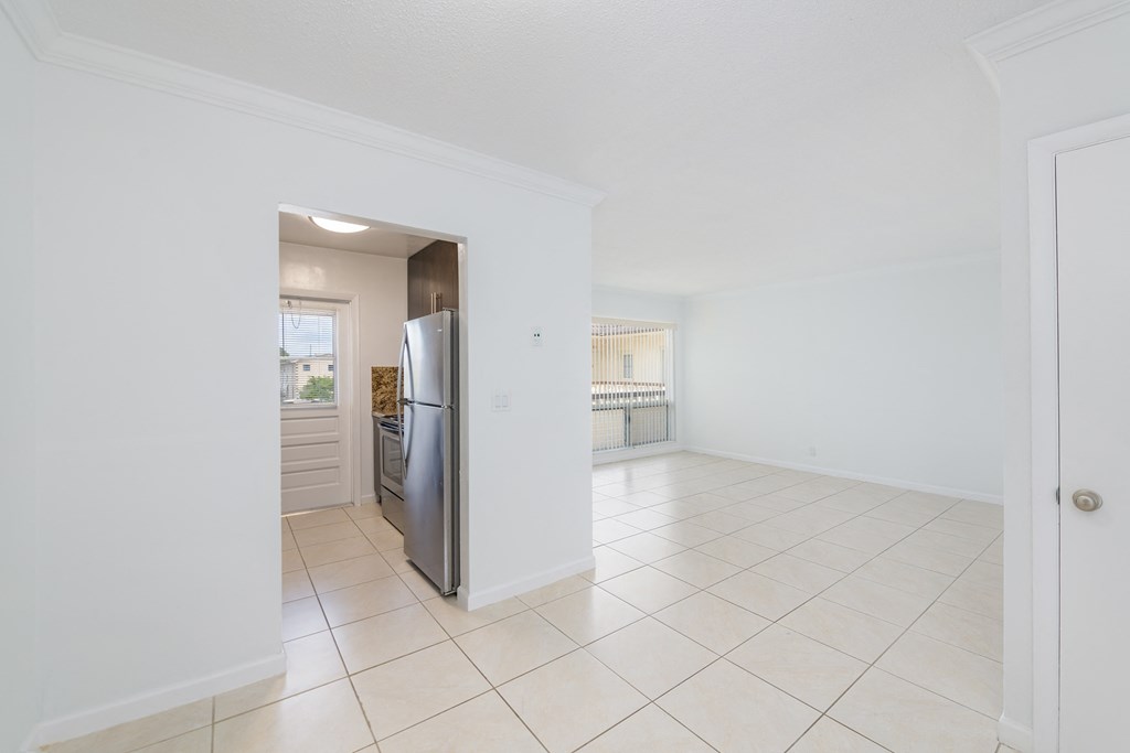 an empty kitchen and living room with a stainless steel refrigerator