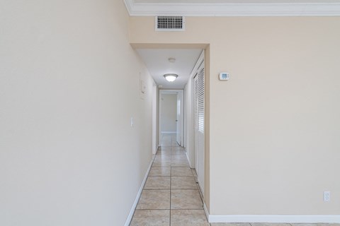 a hallway with white walls and a tile floor and a ceiling fan
