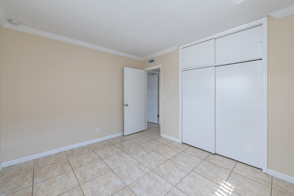 an empty living room with two white closets and a tiled floor