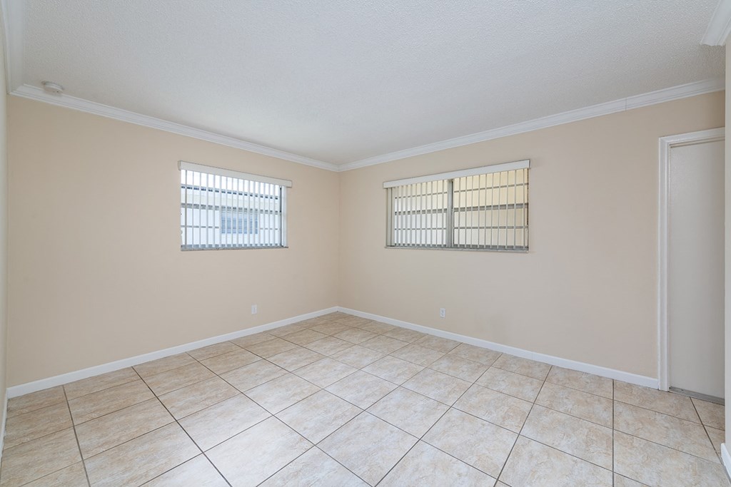 an empty living room with two windows and a tiled floor