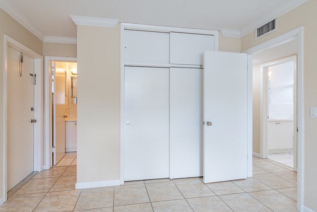 an empty hallway with white closets and a tiled floor