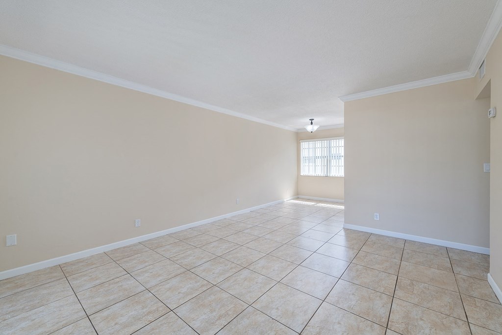 an empty living room with tiled flooring and a window