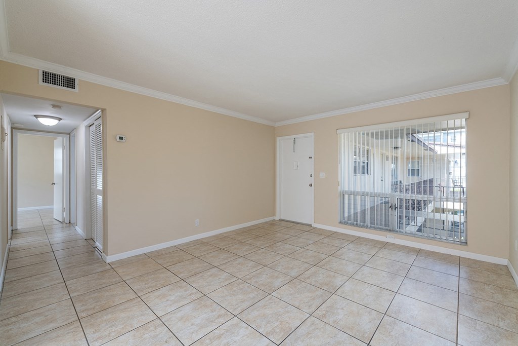 an empty living room with a sliding glass door to a balcony