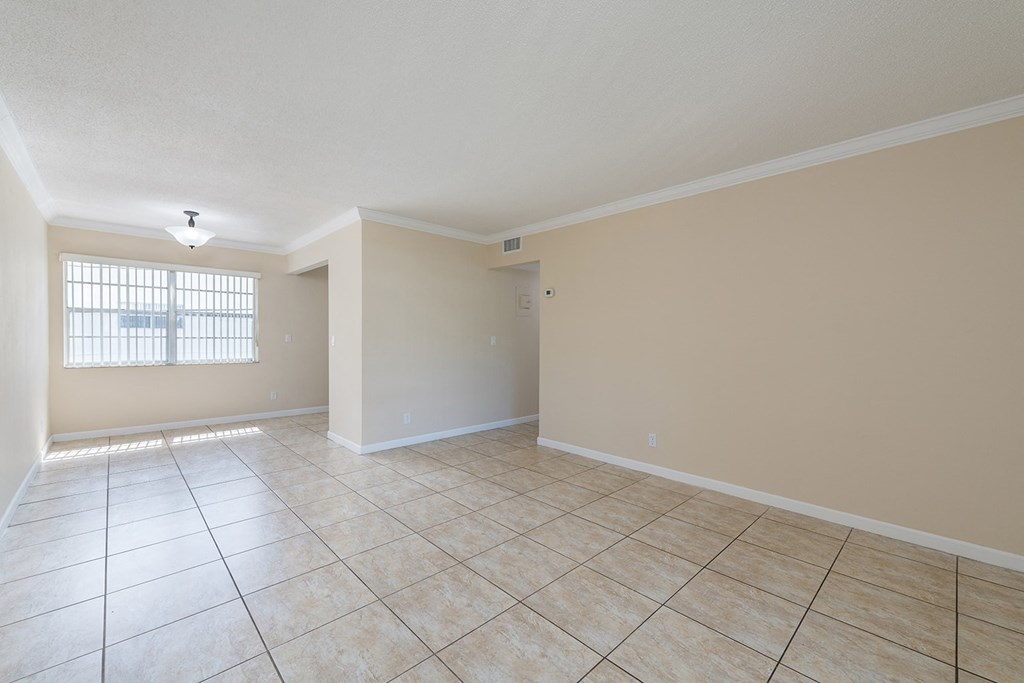 an empty living room with tiled floors and a window