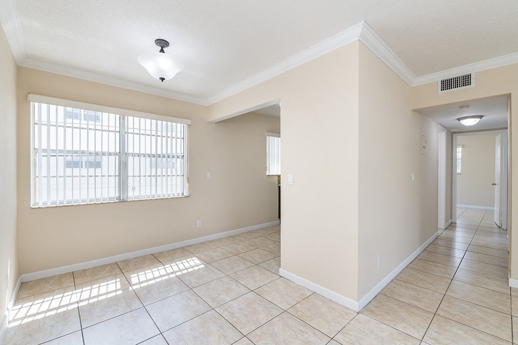 an empty living room with a large window and tiled floors