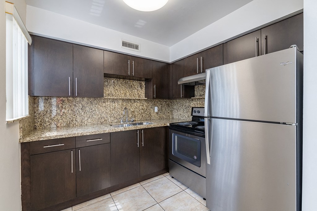 a kitchen with stainless steel appliances and dark wood cabinets