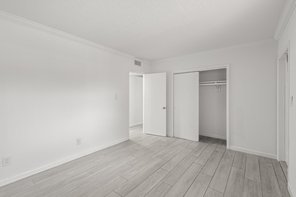 an empty living room with white walls and a door to a closet