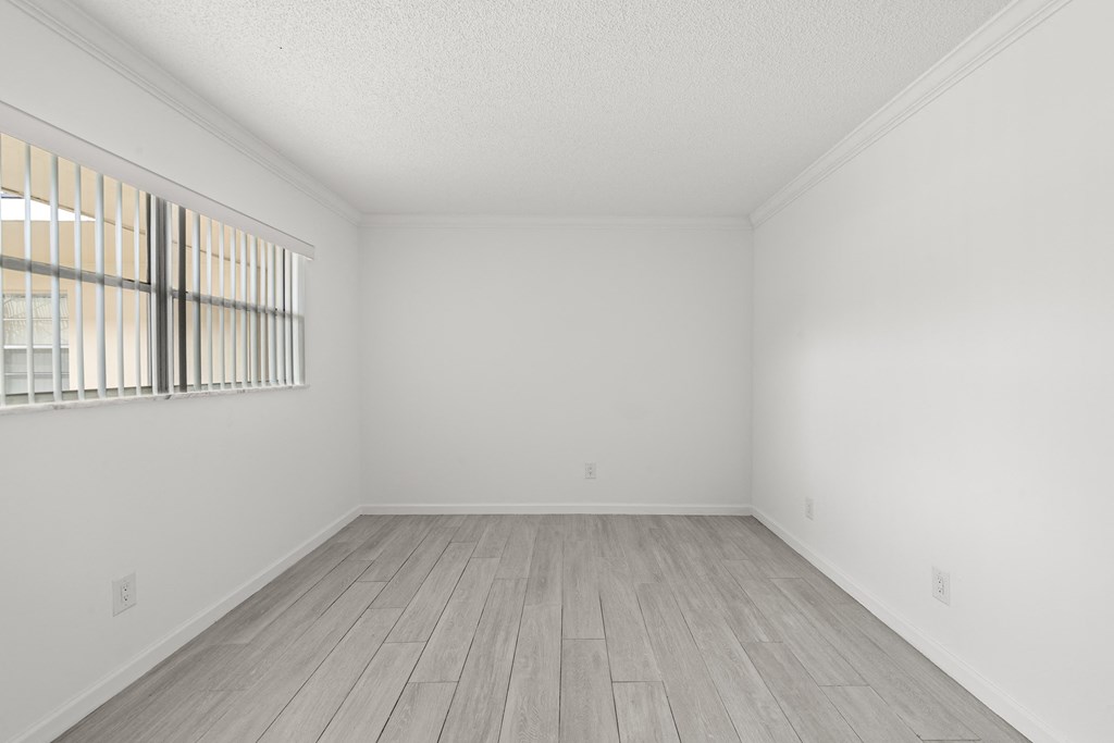 an empty room with white walls and wood floors and a window