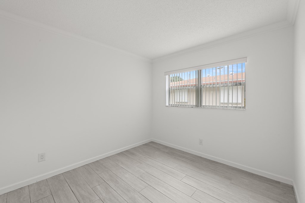 a spacious living room with white walls and a window