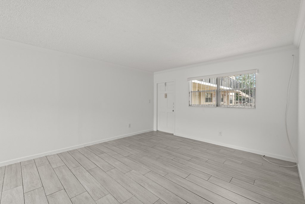 a spacious living room with white walls and wood floors