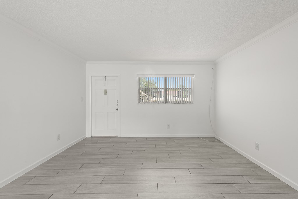a spacious living room with white walls and a white door