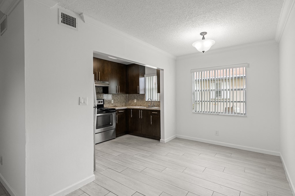 an empty kitchen and living room with white walls and wood flooring