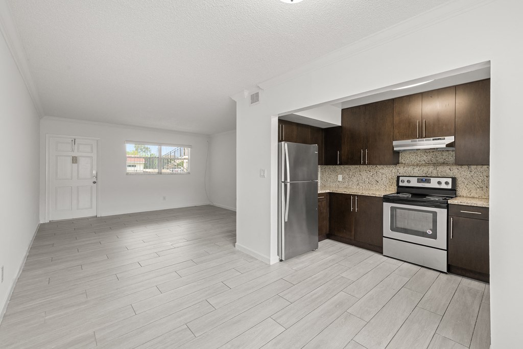 an empty kitchen with stainless steel appliances and wooden cabinets