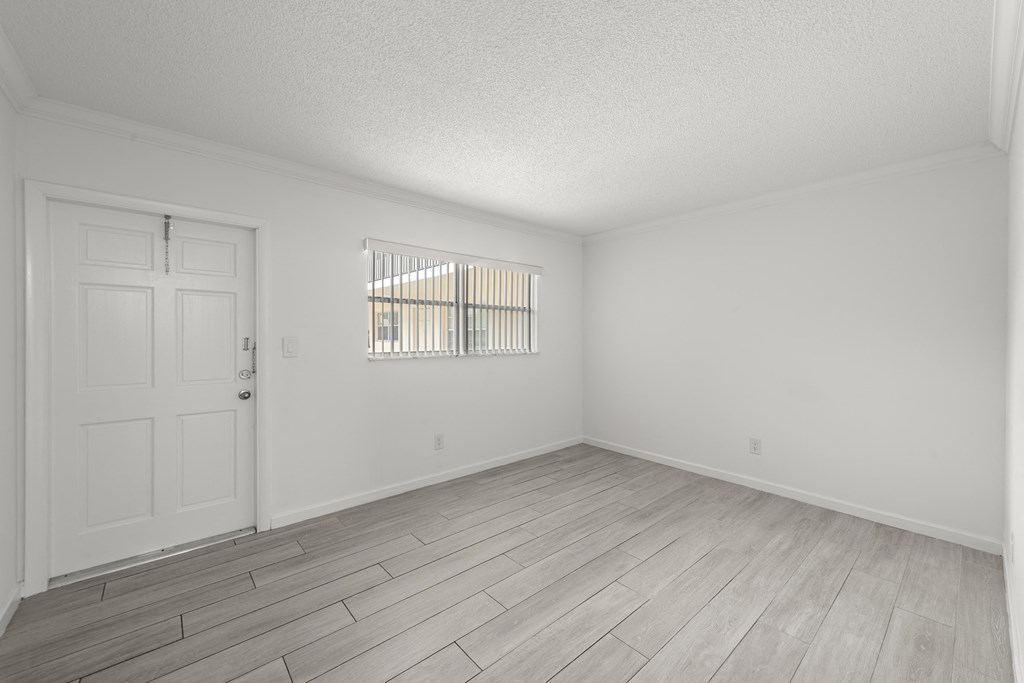 a spacious living room with white walls and wood floors