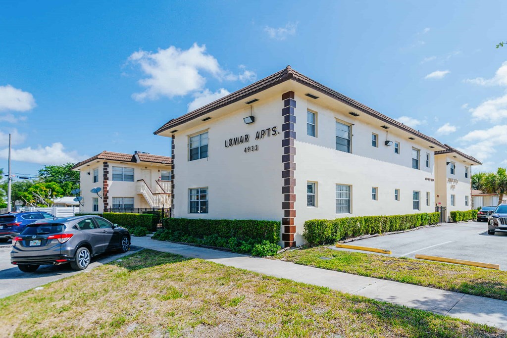 a white apartment building with cars parked in front of it