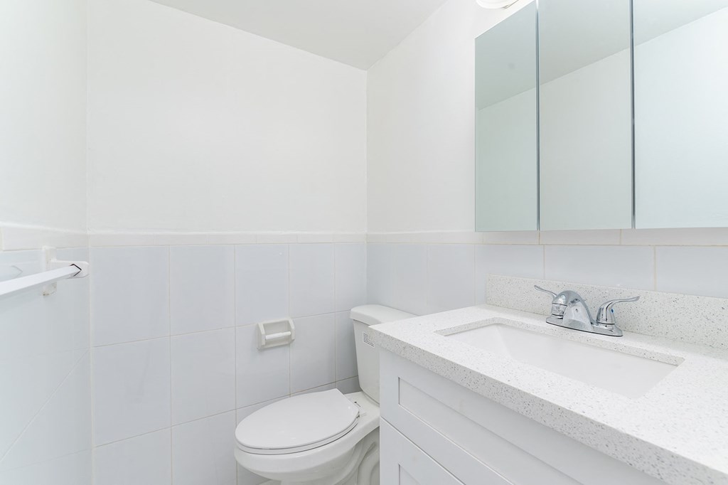 a white bathroom with a sink toilet and mirror