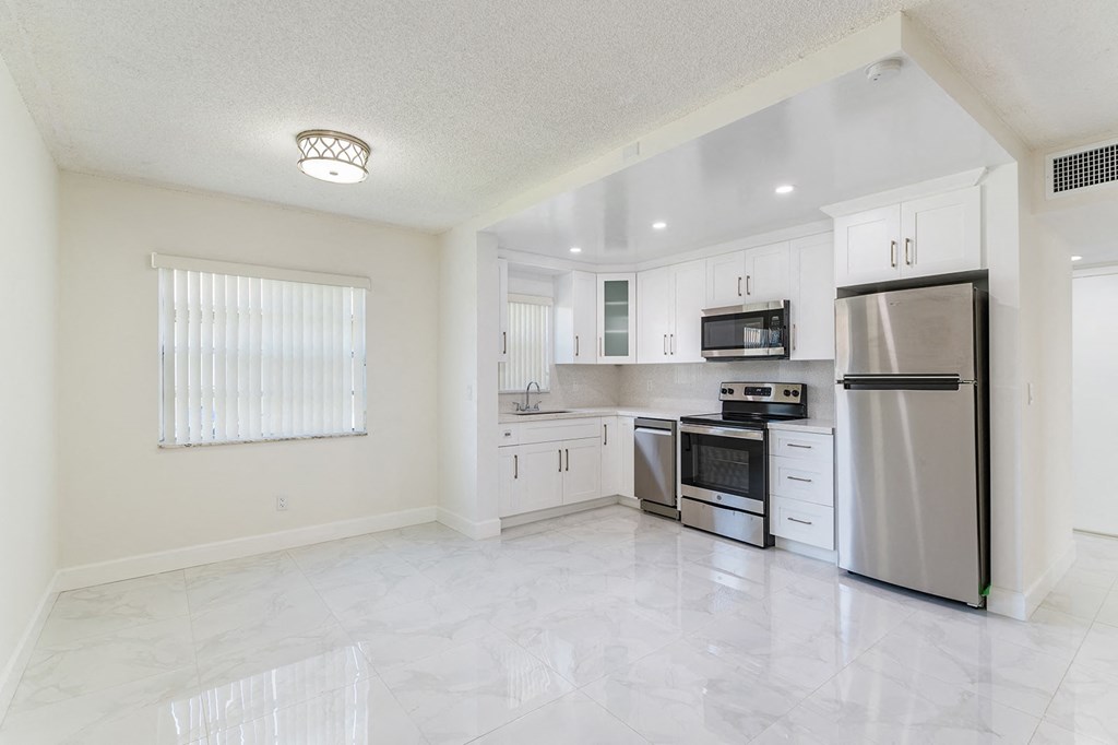 an empty kitchen with stainless steel appliances and white cabinets