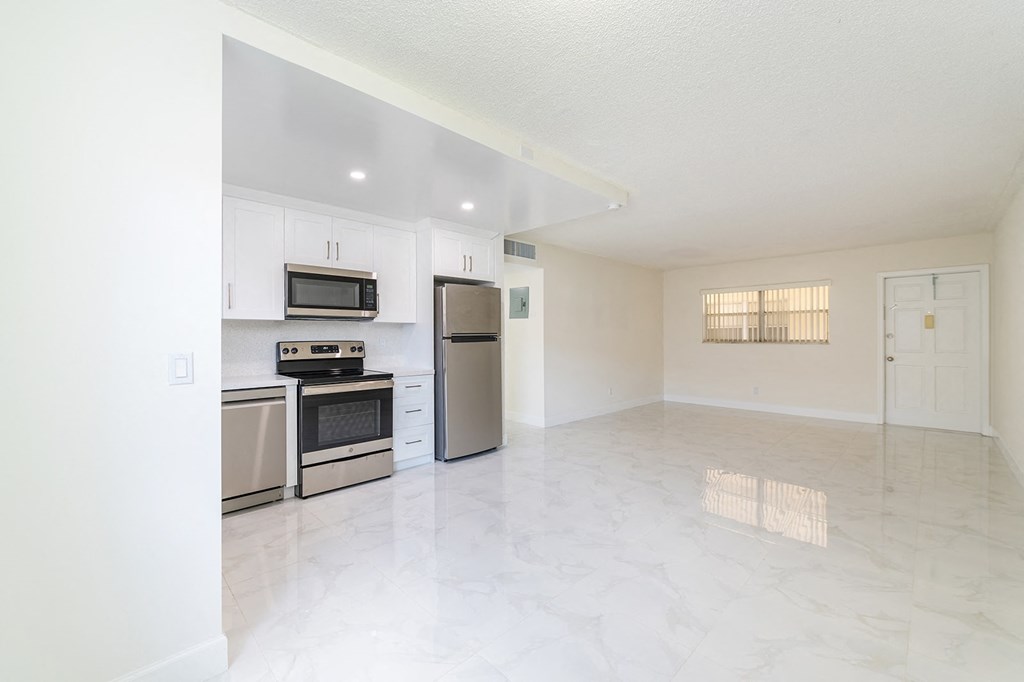 an empty kitchen with stainless steel appliances and white cabinets