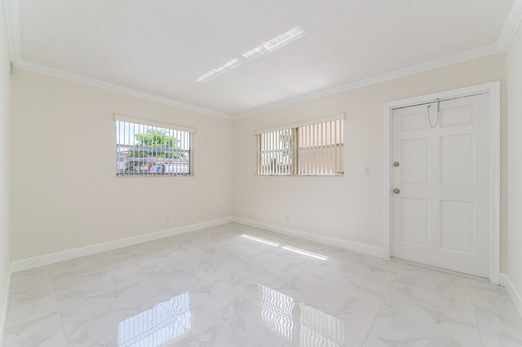 an empty living room with a white door and window