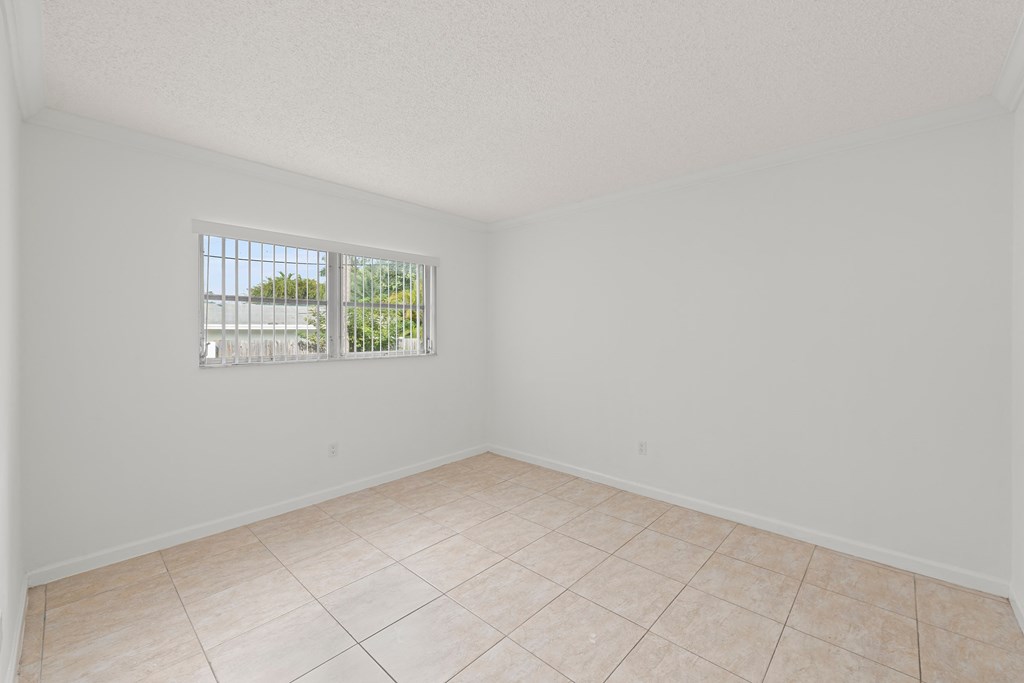 an empty living room with a window and a tiled floor