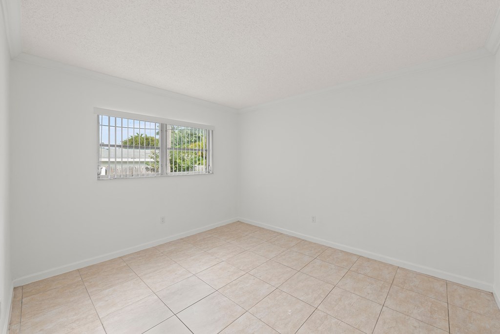 an empty living room with a window and a tiled floor