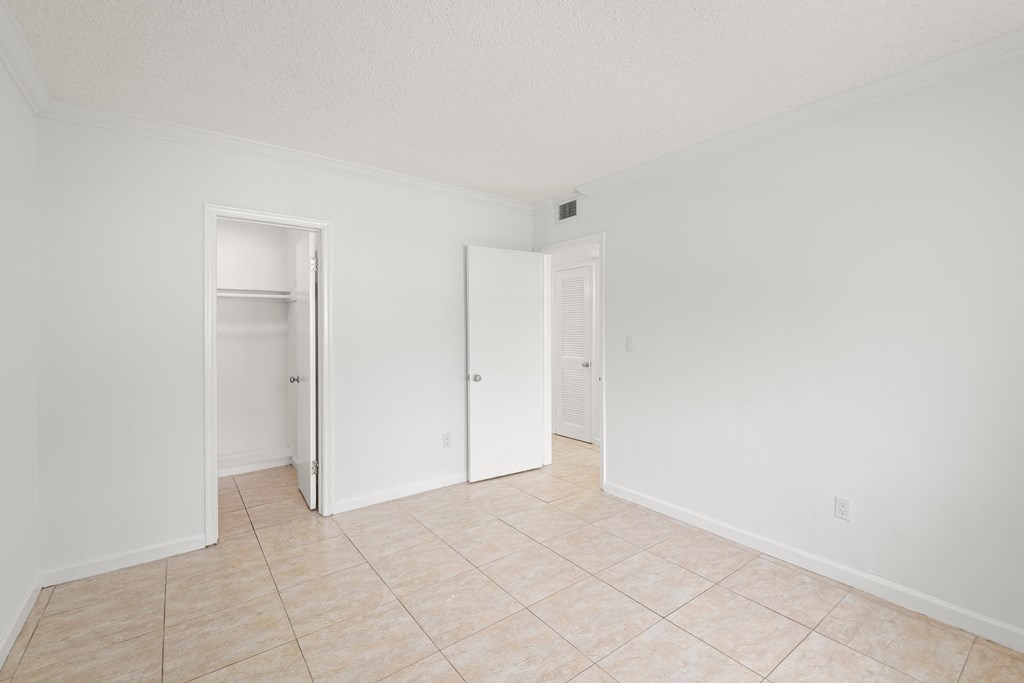 an empty living room with white walls and a tiled floor