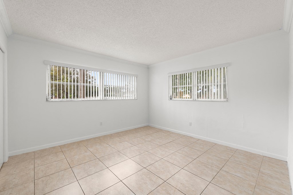 an empty living room with two windows and a tiled floor