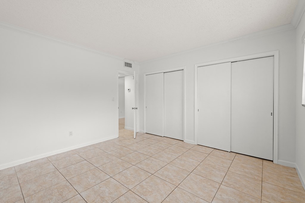an empty living room with white walls and tiled flooring