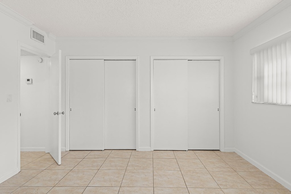 an empty room with white doors and a tiled floor