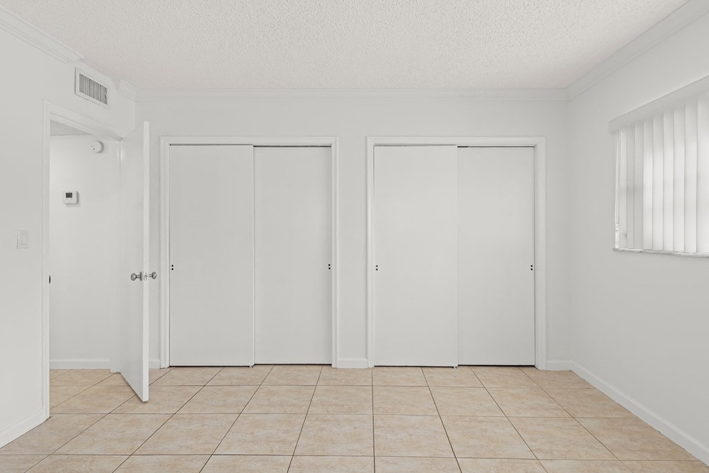 an empty room with white doors and a tiled floor