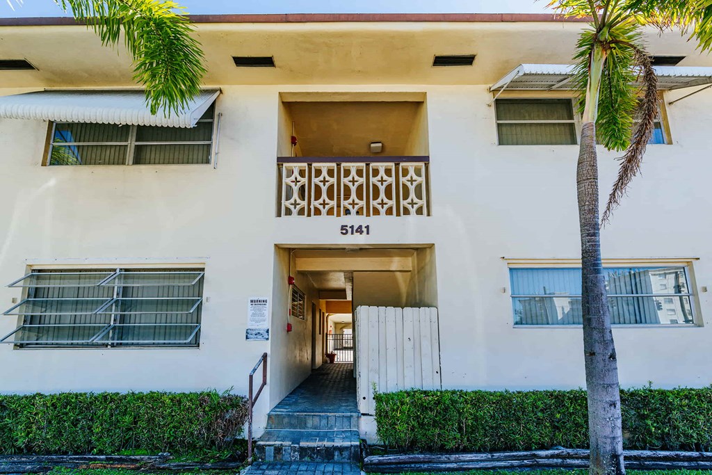 the front entrance to a building with a palm tree in front of it