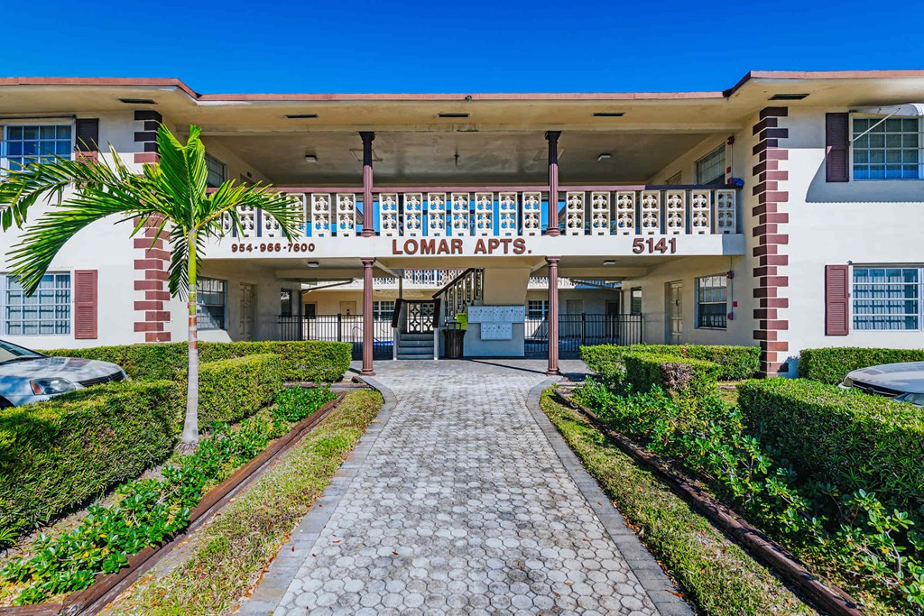 a building with a sidewalk and a palm tree in front of it