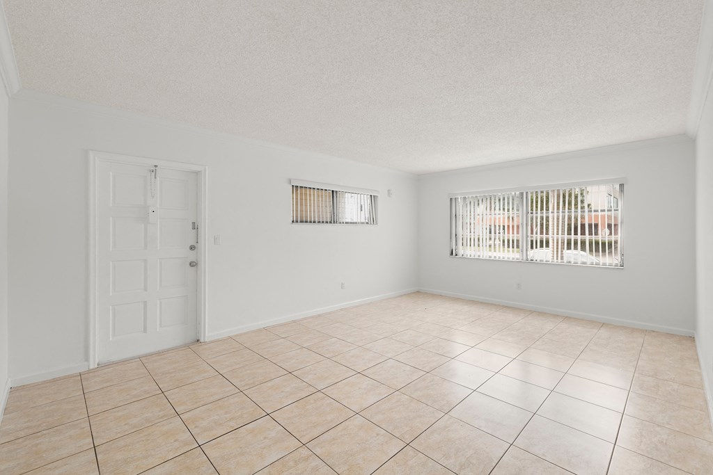 the spacious living room with tiled flooring and a door to the bedroom