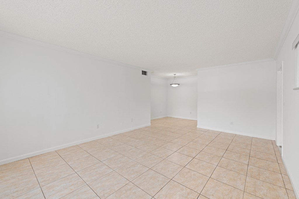 an empty living room with tile flooring and white walls