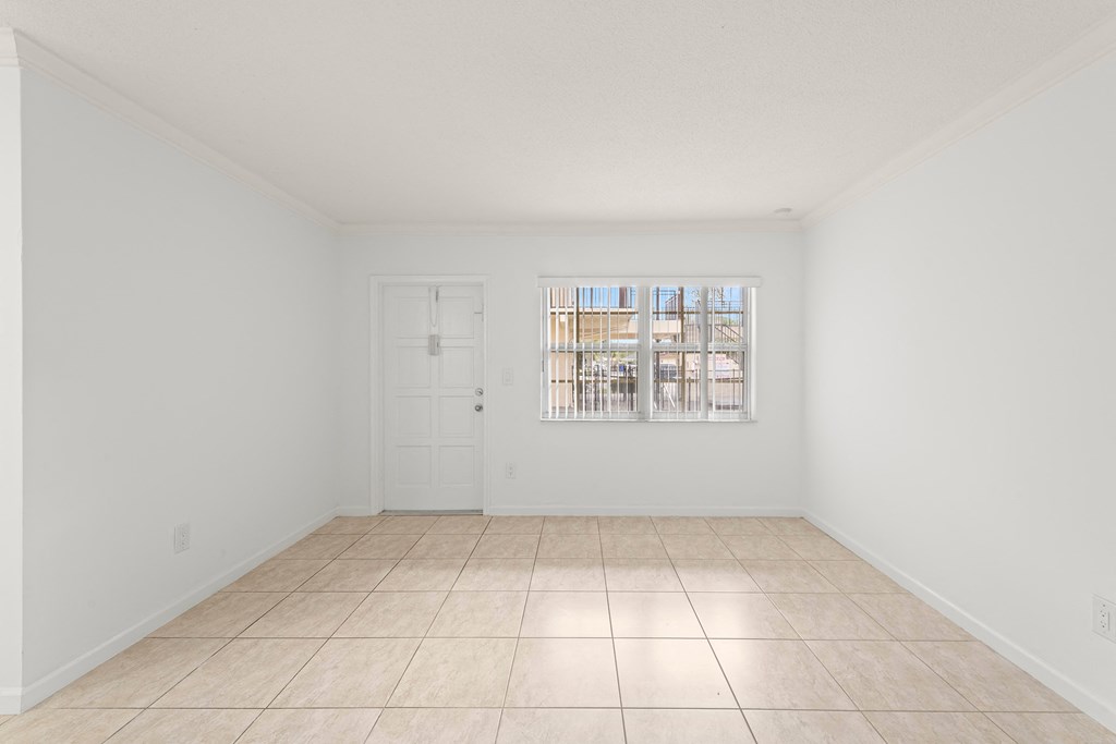 an empty living room with a window and a tiled floor