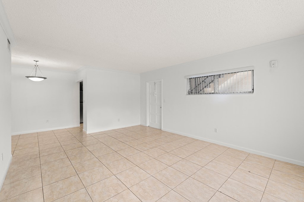 the living room and dining room of an empty house with tile flooring