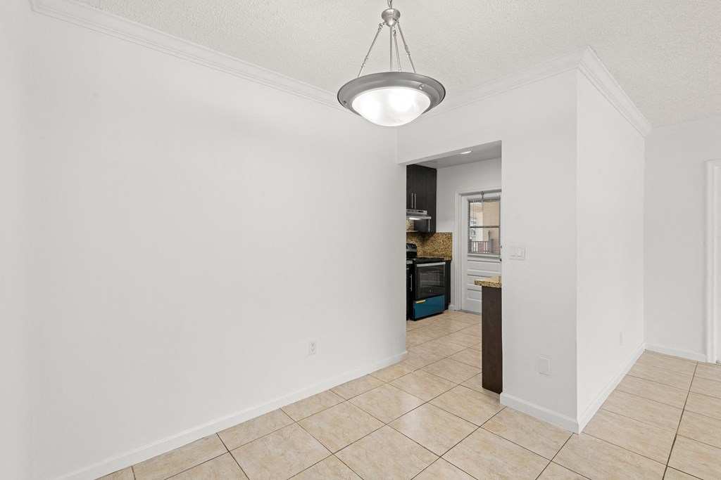 the living room and kitchen of a new home with white walls and tile flooring