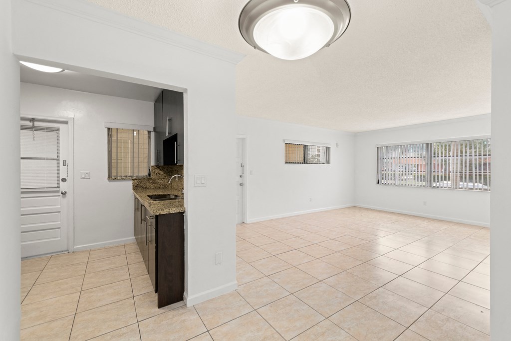 an empty kitchen and living room with a sink and a refrigerator