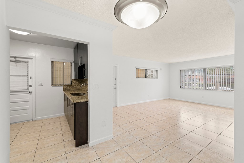 an empty kitchen and living room with a sink and a refrigerator