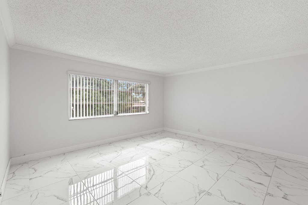 an empty room with a window and white marble floor