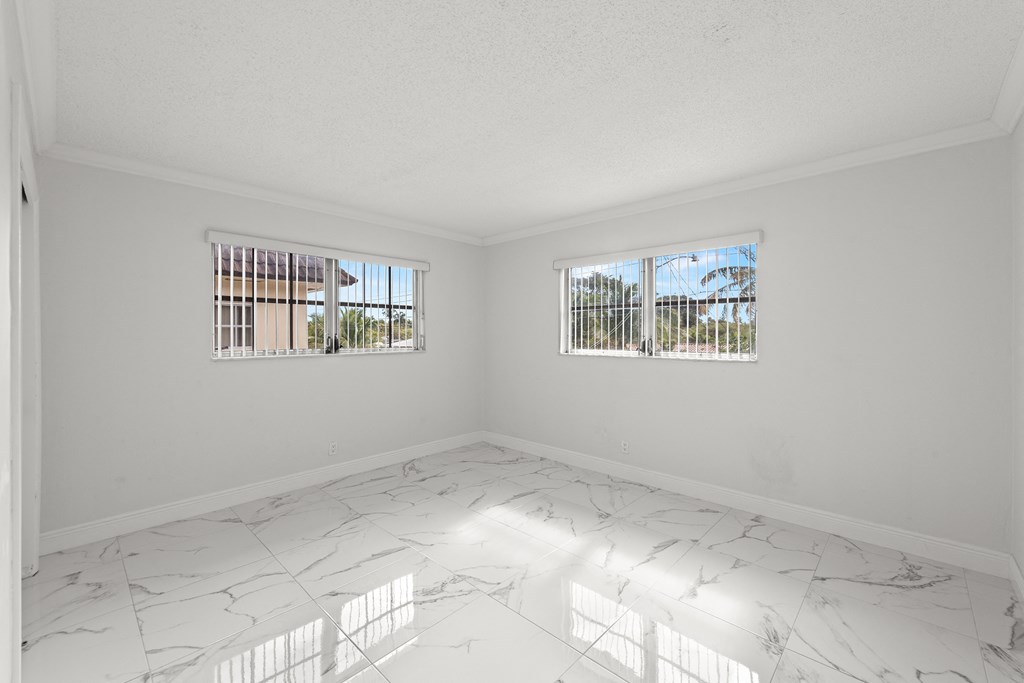 an empty room with two windows and marble floors