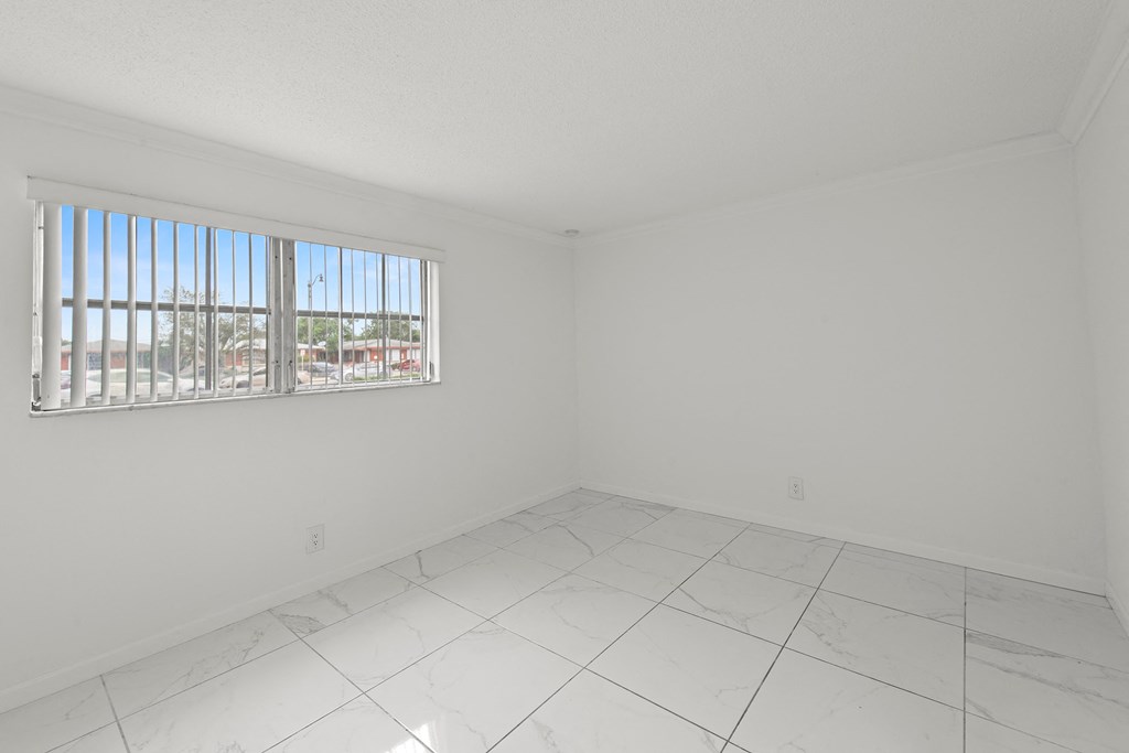 an empty living room with a window and a tiled floor