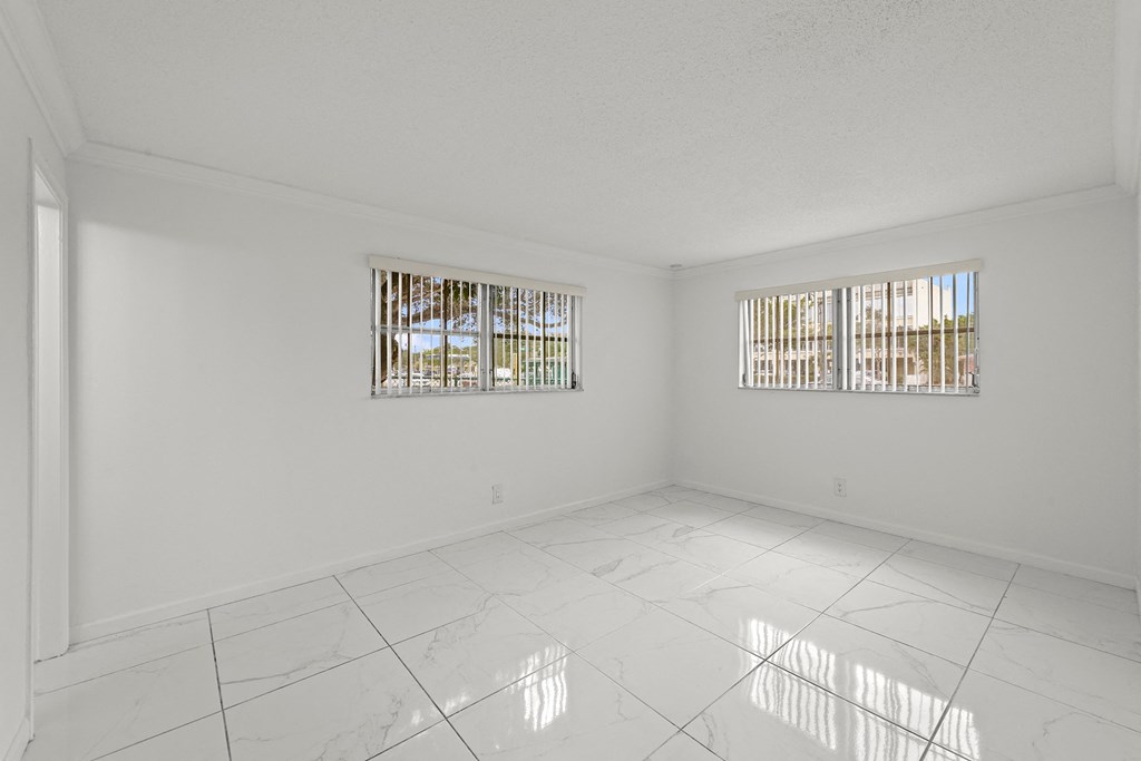 a spacious living room with tile flooring and two windows
