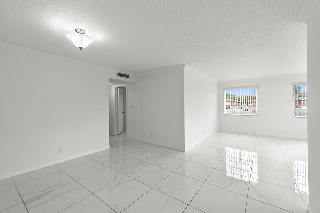 the living room and dining room of an empty house with white walls and tile floors