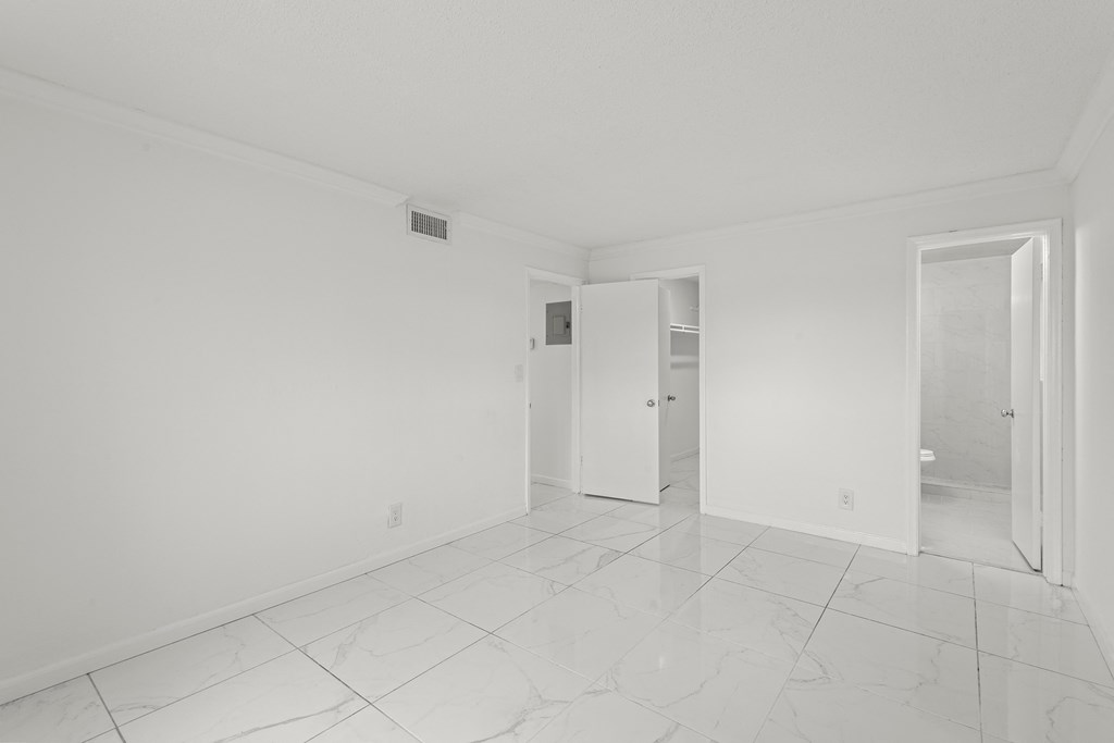 an empty living room with white walls and tile floors
