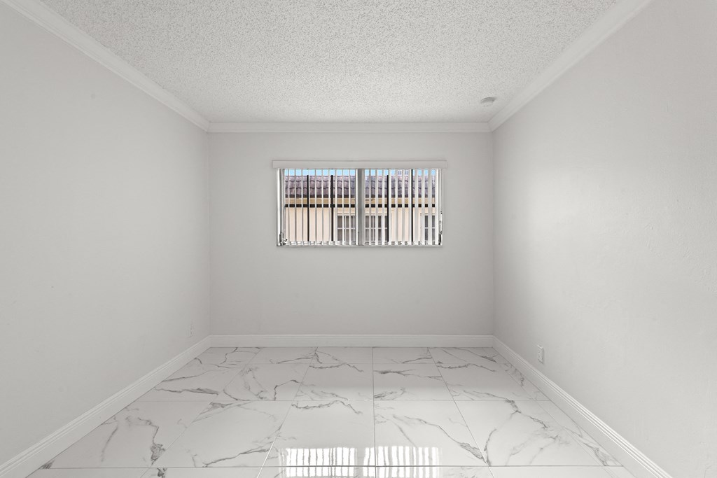 an empty room with a window and marble floors